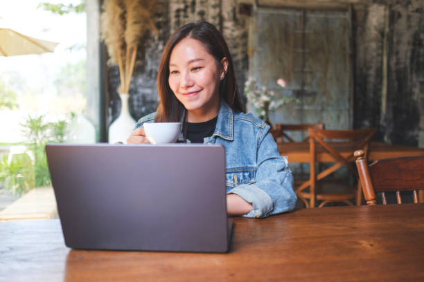 istock Portrait image of a young woman drinking coffee while working on laptop computer in cafe 2151833719
