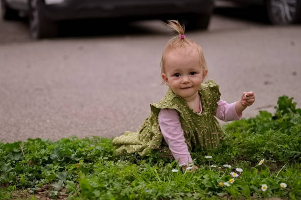 A little girl is crouching in the grass and picking flowers