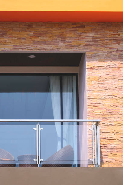 istock Rattan chair and table set with glass baluster on balcony and cladding stone brick tile wall on modern beige house in vertical frame 2151835453