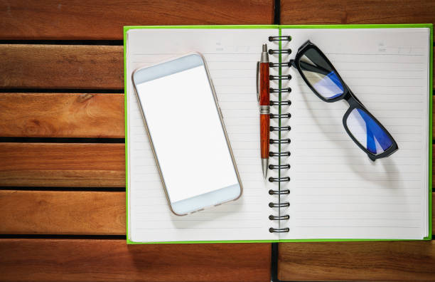 Smartphones , Book with pencil and glasses on wood floor background of top view