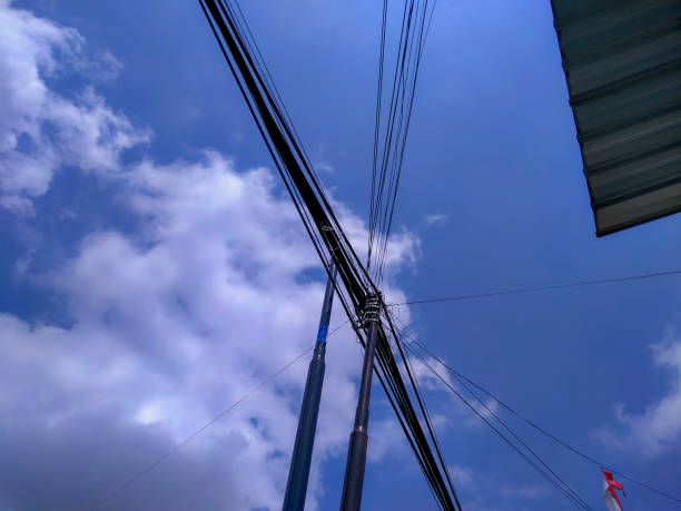 An electric pole against a bright blue sky background.