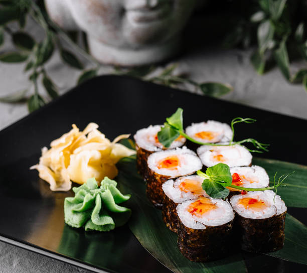 istock Sushi array garnished with wasabi and ginger on a stylish black plate, adorned with greenery 2151838271