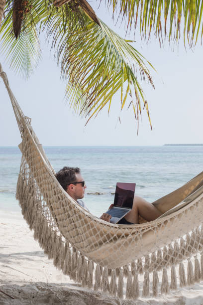 istock freelancer man with laptop working online on the beach in hammock 2151839573