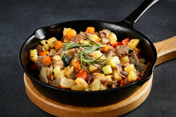 istock Savory cast-iron skillet ragout with tender meat and colorful vegetables on a textured black table 2151844949