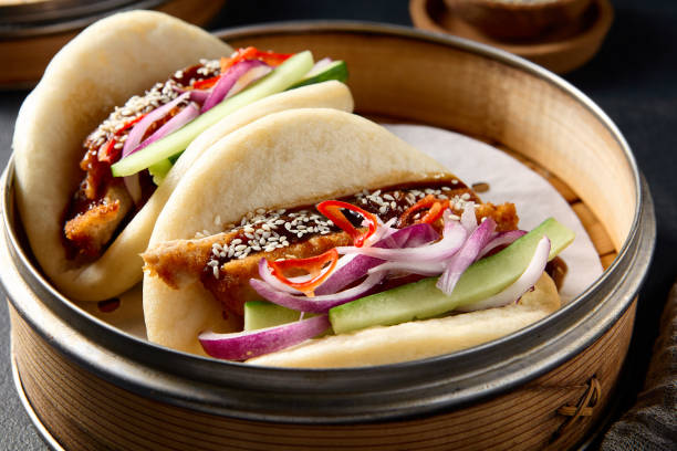 istock Authentic Asian cuisine: Bao buns with duck and vegetables in a steamer on a black table 2151845003