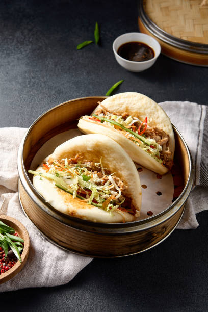 istock Savory Bao buns stuffed with pulled pork and fresh vegetables, captured from above on a dark background 2151845004