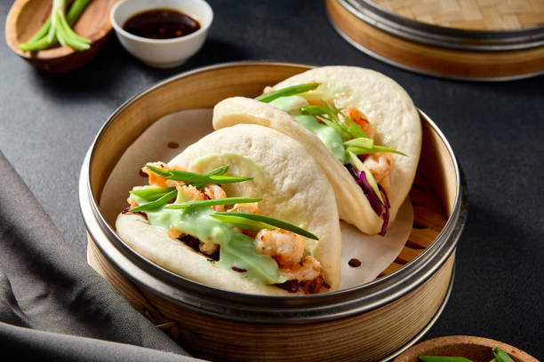 istock Steamed Bao buns filled with shrimp, purple cabbage, and wasabi, served on a dark table setting 2151845005