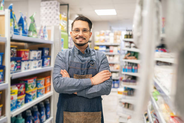 istock Confident man business owner of a supermarket standing between shelves while facing camera smiling 2151846189