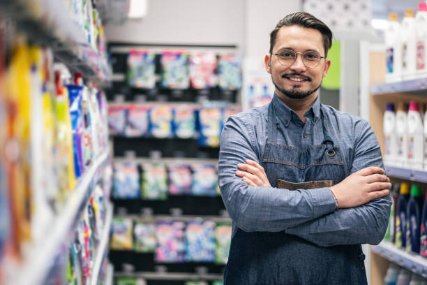 istock Successful business owner of a supermarket standing between shelves while facing camera smiling 2151846191