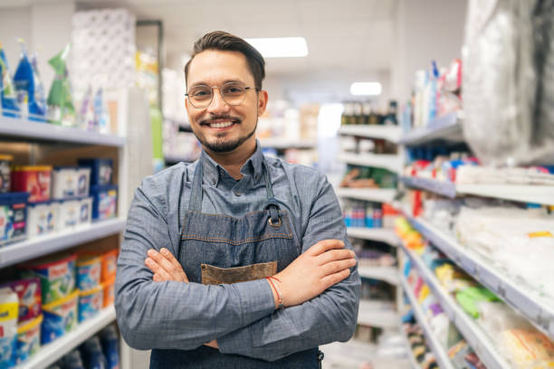 istock Confident man business owner of a supermarket standing between shelves while facing camera smiling 2151846193