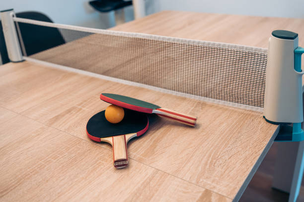 istock Pingpong paddles and net on indoor table at home. Portable mini pingpong set installed on a wooden table at home. 2151850892