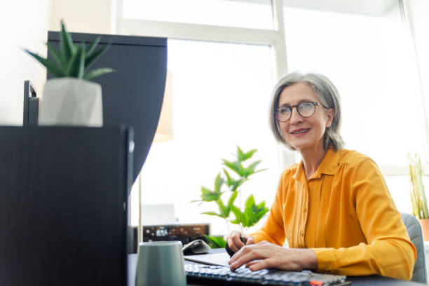 istock Focused smiling senior woman, graphic designer, editor, retoucher using tablet working 2151852933