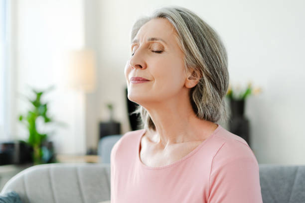 istock Smiling active senior woman sitting with closed eyes on comfortable sofa relaxing at home 2151852969