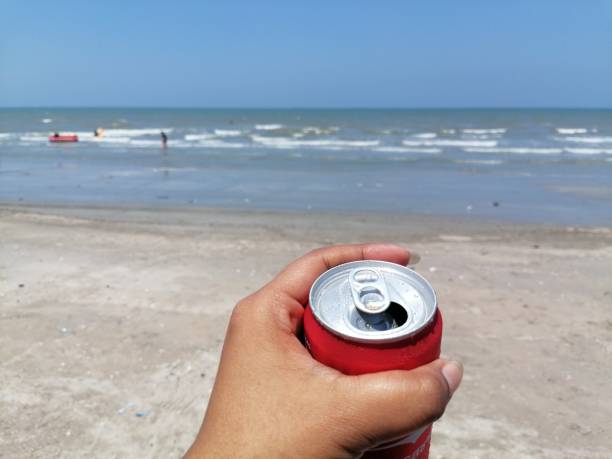 Cola can and hand woman on the beach