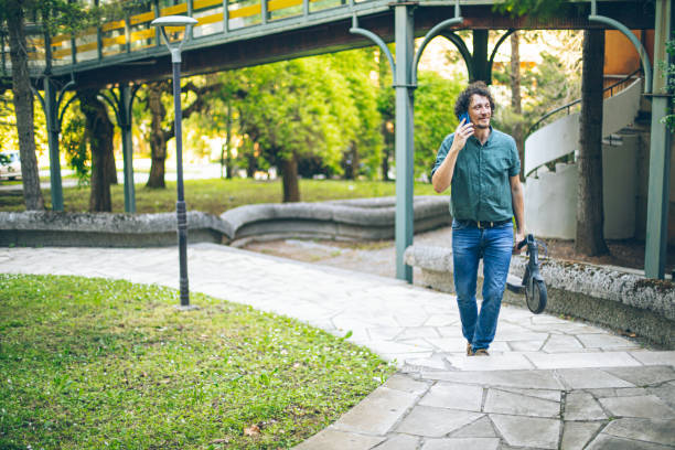 istock Man walking on stairs with an electric scooter while talking on mobile phone 2151858623