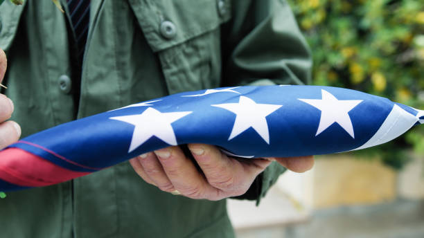 istock Folded Flag In Commemoration Of American Fallen Held In Hand 2151859844