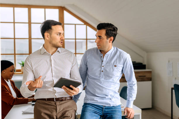 istock Two well dressed male colleagues using digital tablet at the modern office 2151860819