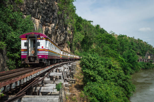 A train moves on a beautifully cut wooden bridge on May 1, 2022, Kanchanaburi Province, Thailand.