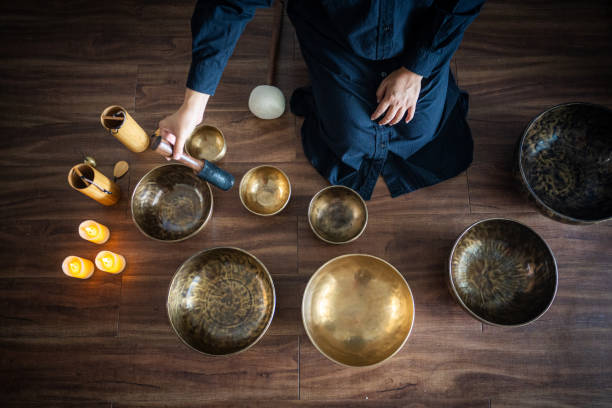 Top view of Woman playing Tibetan singing bowls for meditation. Tibetan singing bowls can be powerful tools for deepening your meditation practice and cultivating inner peace.