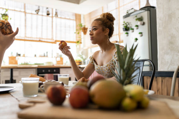 istock Young Woman Enjoying Fresh Fruit During a Friendly Breakfast Conversation 2151869810