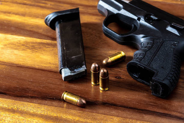 istock 9 mm gun with bullets on wooden background 2151872274