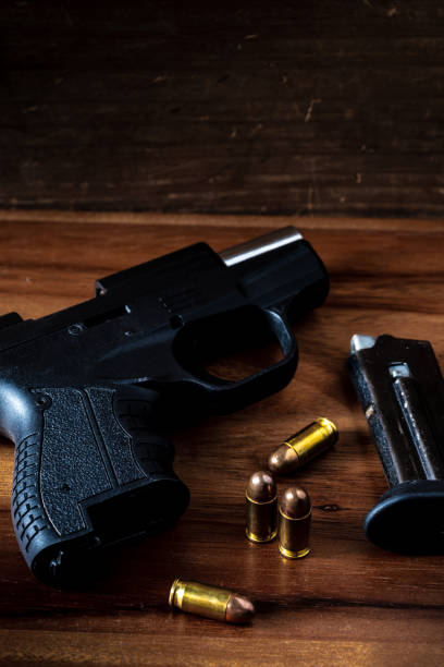 istock 9 mm gun with bullets on wooden background 2151872286