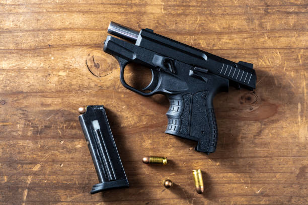 istock 9 mm gun with bullets on wooden background 2151872317