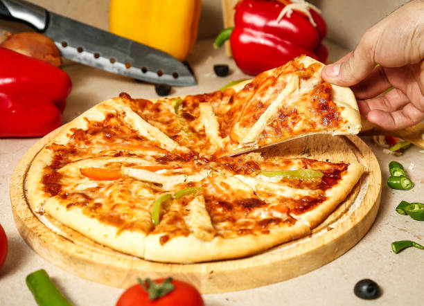 istock Person Cutting Pizza on a Wooden Cutting Board 2151873106