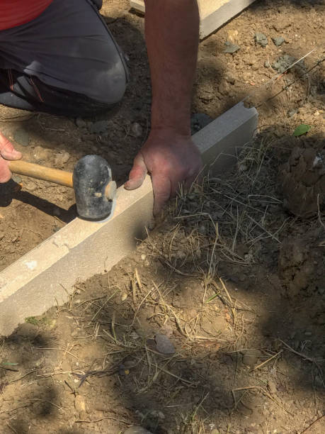 istock Setting edge restraints buy putting border curb stones in earth-moist concrete 2151874829