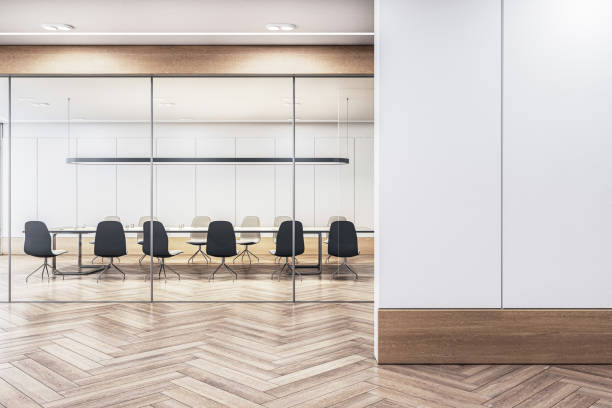 istock Modern boardroom with a long table and chairs, visible through glass partitions, against a clean, empty wall for mockup. 3D Rendering 2151876642