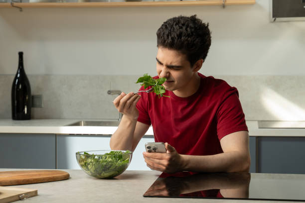 Young Man Experiences Disappointment With Bland Salad in Modern Kitchen During Lunchtime