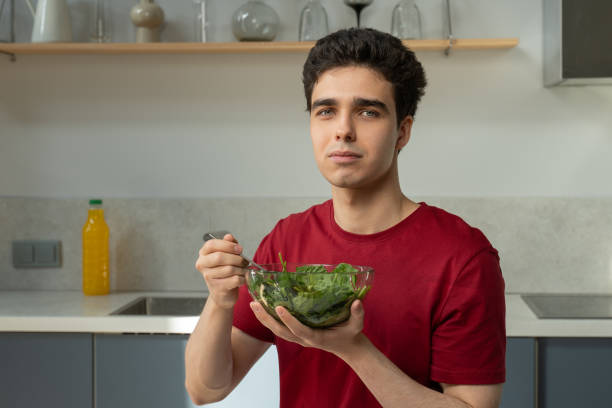 istock Young Man Enjoying Fresh Salad in a Modern Kitchen During Lunchtime 2151878160