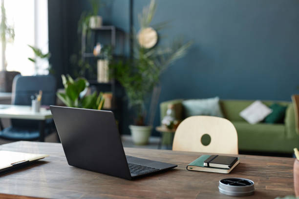 Laptop at Workplace Table in Office with Blue Wall