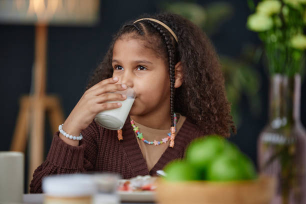 istock Black Girl Drinking Milk Sitting at Dining Table at Breakfast 2151882575