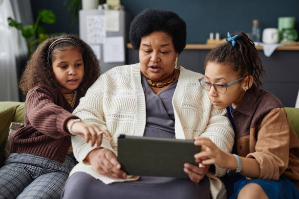 istock Black Senior Woman Using Digital Tablet with Two Children Helping 2151882584