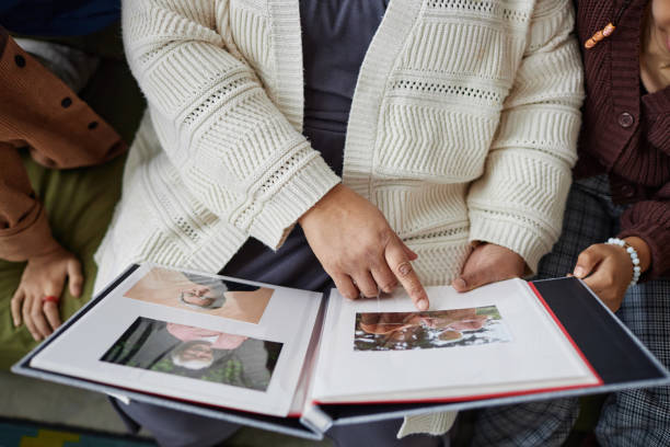 Close Up of Senior Woman with Two Children Looking at Photos Close up of senior woman with two children looking at pictures in photo album and sharing family history copy space pics of the black granny stock pictures, royalty-free photos & images