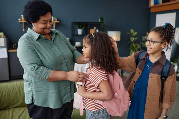 istock Smiling Black Grandma Helping Two Girls Getting Ready for School 2151882623