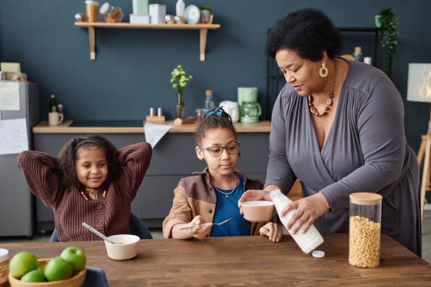 istock Black Grandma Serving Breakfast to Girls at Kitchen Table 2151882655