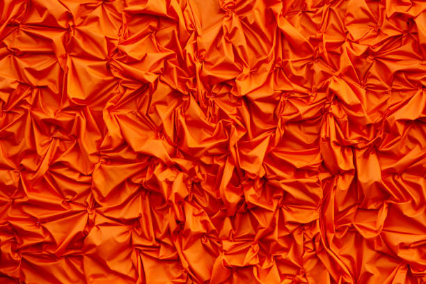Orange silk crumpled fabric as an abstract background. Texture.