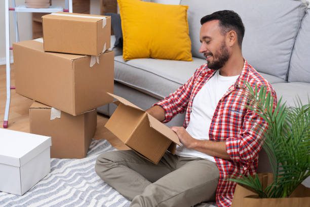 istock New owner with smile holds box in hands sitting on floor 2151885939