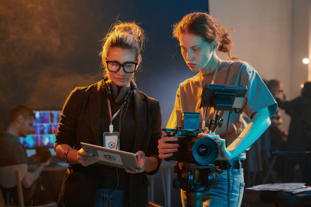 Two Women Working in Video Production And Using Tablet Waist up portrait of two women working in video production crew and looking at digital tablet screen copy space film-crew stock pictures, royalty-free photos & images