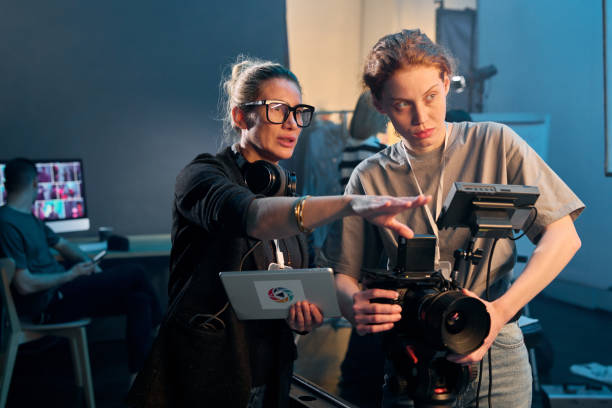 Female Director Giving Instructions on Set Waist up portrait of female director giving instructions working in video production and operating cameras copy space film-crew stock pictures, royalty-free photos & images