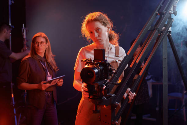 istock Camerawoman Operating Equipment in Studio with Red Neon Light 2151886118