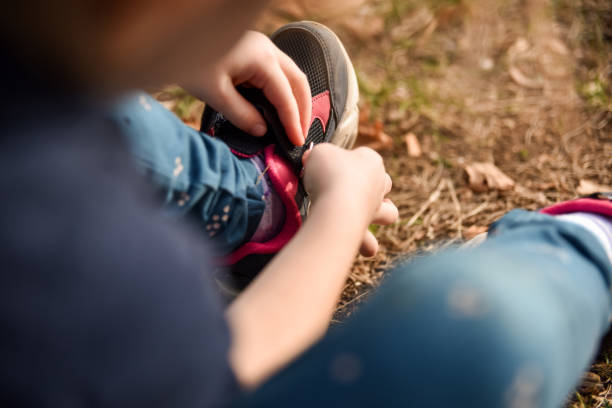 Little girl putting on her shoes while her friends are waiting to play