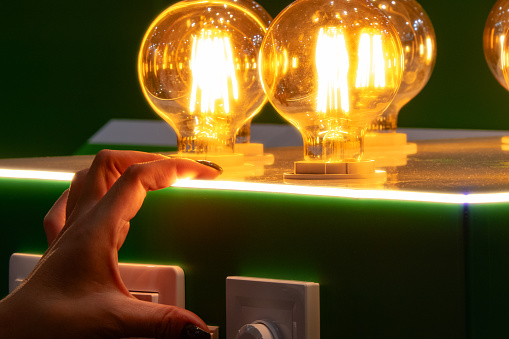 A man turns on round energy-efficient light bulbs in a glass bulb with warm light