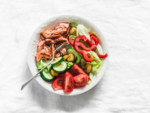 Delicious balanced lunch - grilled salmon, boiled egg, fresh vegetable salad on a light background, top view