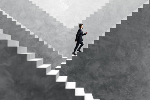 istock Side view happy young businessman walking on various concrete success stairs on light background. Career ladder and promotion concept. 2151897482