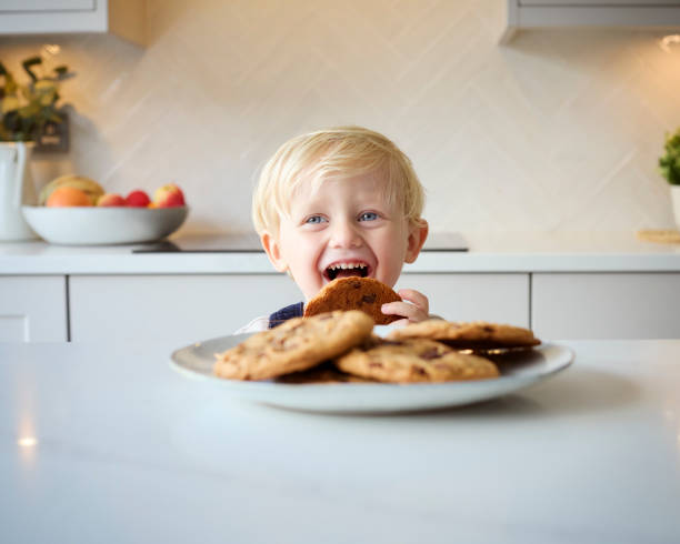 istock Mischievous Young Boy Eating Giant Cookie From Plate In Kitchen At Home 2151906033