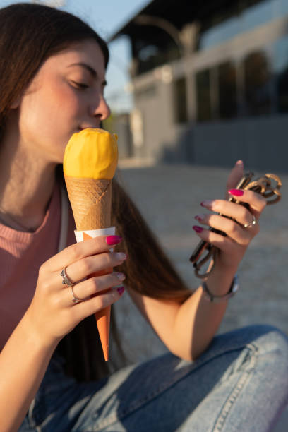 istock A woman is eating an ice cream cone while looking at her phone. Summer holidays. 2151907523