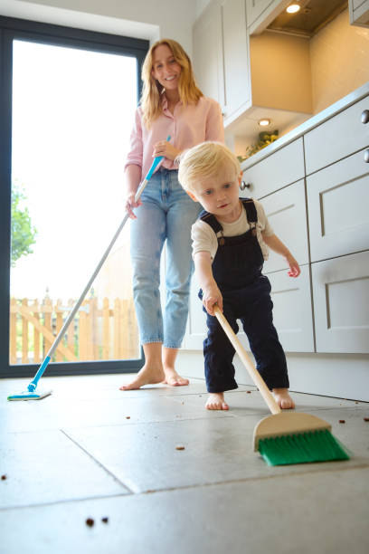 istock Mother With Young Son At Home In Kitchen Helping With Housework Sweeping Floor 2151909029